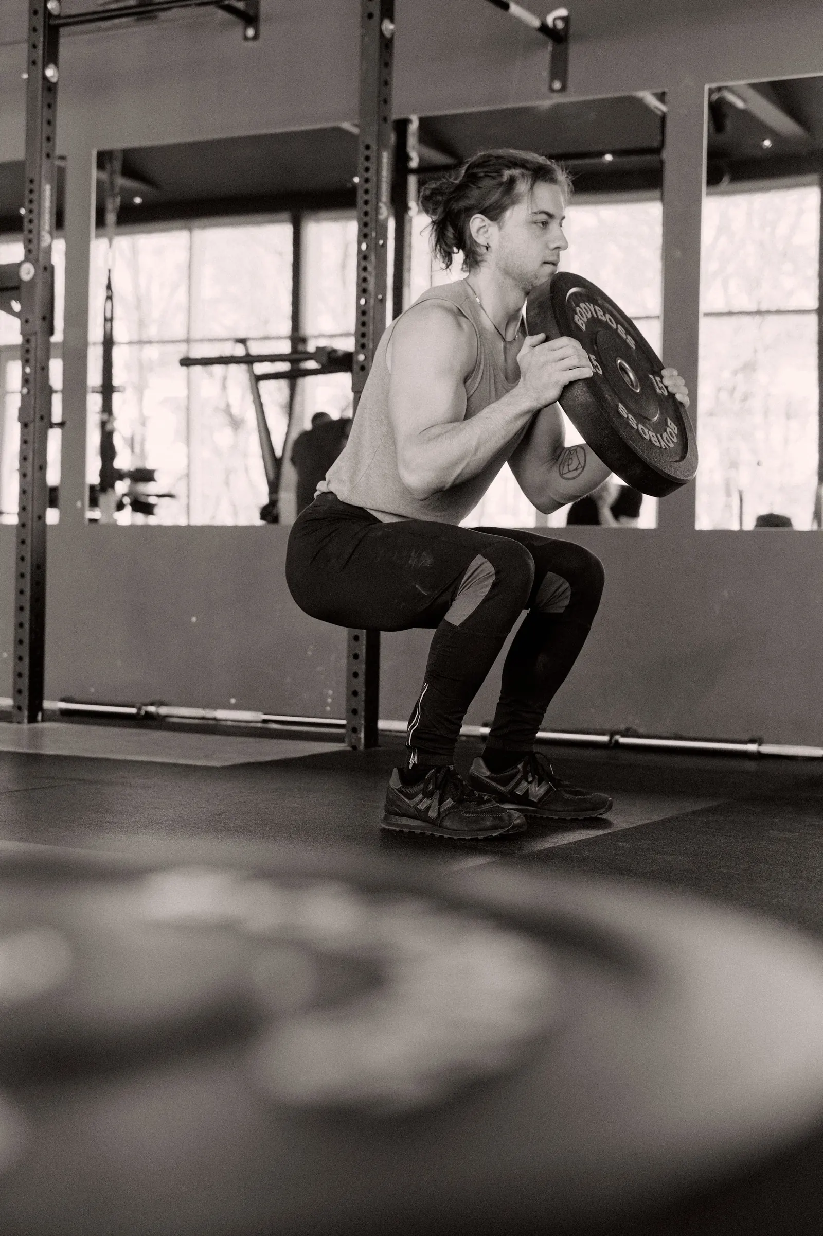 Black-and-white photo of a man squatting with a barbell